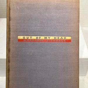 May include: A vintage book titled "Out of My Head" by Margaret Fishback. The book has a faded purple cover with a rectangular label in red, gold, and white. The book is propped up by a decorative rooster figurine.