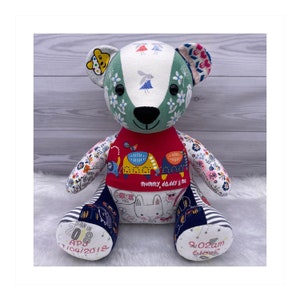 May include: A patchwork teddy bear with a red bib that says "Mummy, daddy & me". The bear is made from different fabrics with various patterns, including flowers, elephants, and a bunny. The bear's paws have embroidered details, including the date "08 APR 2018" and the time "9:02am".