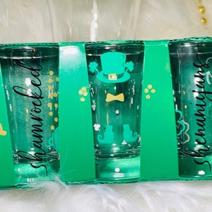 May include: Set of three green shot glasses with a leprechaun design and the words "Shamrocked" and "Shenanigans".