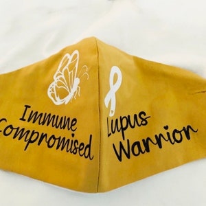 May include: A yellow face mask with a white butterfly and the text "Immune Compromised" on one side and a white ribbon with the text "Lupus Warrior" on the other side.