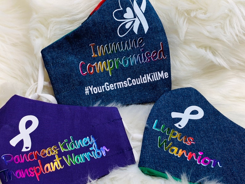 May include: Three denim face masks with white ribbon designs and rainbow text. The top mask reads "Immune Compromised #YourGermsCouldKillMe". The middle mask reads "Pancreas Kidney Transplant Warrior". The bottom mask reads "Lupus Warrior".