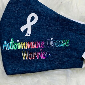 May include: A blue denim face mask with a white ribbon and the text "Autoimmune Disease Warrior" in rainbow glitter.