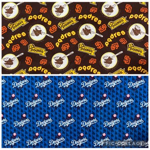 May include: Two fabric patterns: one brown with San Diego Padres logos and text, the other blue with Los Angeles Dodgers logos and text. The Padres pattern features the team's logo and the word "padres" in yellow and orange. The Dodgers pattern has the team's logo and the word "Dodgers" in white.