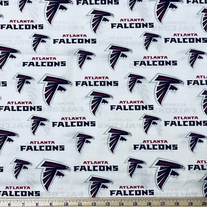 May include: White fabric with a repeating pattern of the Atlanta Falcons logo. The logo is a red and black falcon head with the words "Atlanta Falcons" printed below it.
