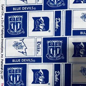 May include: White fabric with a repeating pattern of blue squares featuring Duke University logos and text. The design includes the Blue Devils logo, the word "Duke", and the phrase "Home of the Blue Devils".