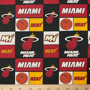 May include: Black and red fabric with a repeating pattern of the Miami Heat basketball team logo, the words "Miami Heat", and a basketball. The fabric is a checkered pattern with black, red, white, and yellow squares.