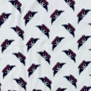 May include: White fabric with a repeating pattern of red and black winged crowns.