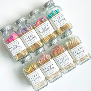 May include: Eight glass jars filled with wooden matches with colorful tips. Each jar has a label that reads "URBAN BURN CANDLE CO. SAFETY matches QUANTITY: 70".