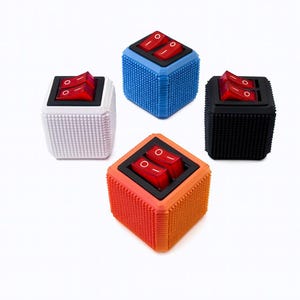 Peut inclure: Quatre objets cubiques colorés avec des interrupteurs à bascule rouges. Les cubes sont blancs, bleus, noirs et orange, chacun avec une surface texturée. Les interrupteurs sont dans un carré noir.