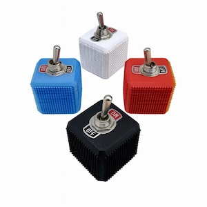May include: Four colourful toggle switches. The switches are cube-shaped with a textured surface and a silver toggle. The colours are white, blue, red, and black. Each switch has "ON" and "OFF" labels.