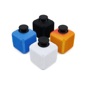 Puede incluir: Cuatro tapones de botella cuadrados en azul, negro, blanco y naranja. Cada uno tiene una superficie texturizada y un mango negro y redondo. Los tapones están diseñados para encajar perfectamente en la abertura de una botella.