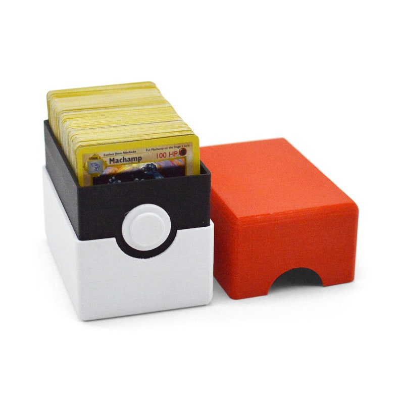 May include: A white and black Pokemon card storage box with a red lid. The box is open and filled with yellow Pokemon cards. The top card shows a Machop Pokemon with the text "Machop 100 HP".
