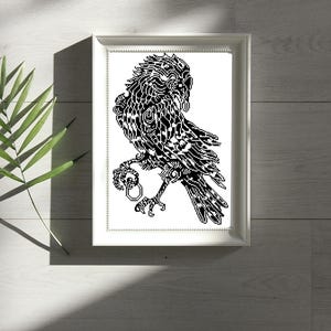 May include: A white rectangular frame containing a black and white cross-stitch pattern of a raven holding a ring in its claw. The bird features intricate geometric and tribal-style patterns throughout its feathers, wings, and body.