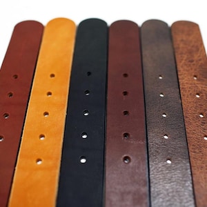 May include: Seven leather belts in different colors, including brown, tan, black, and dark brown. The belts have multiple holes for adjusting the fit.