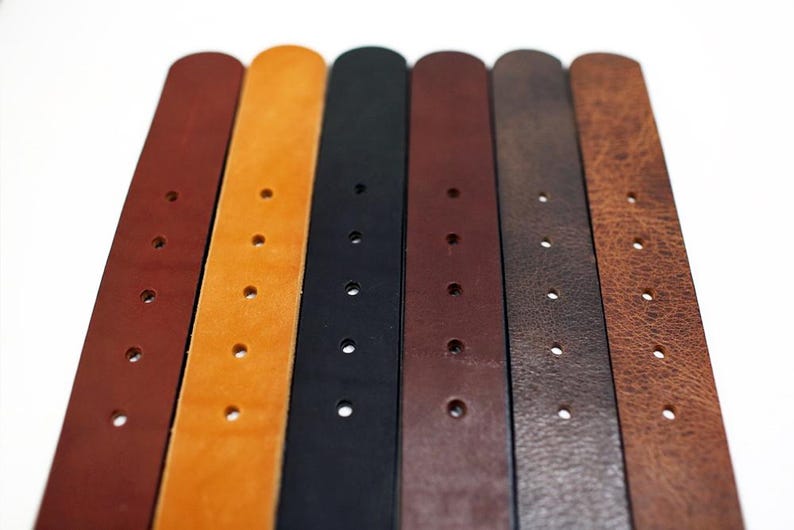 May include: Seven leather belts in different colors, including brown, tan, black, and dark brown. The belts have multiple holes for adjusting the fit.
