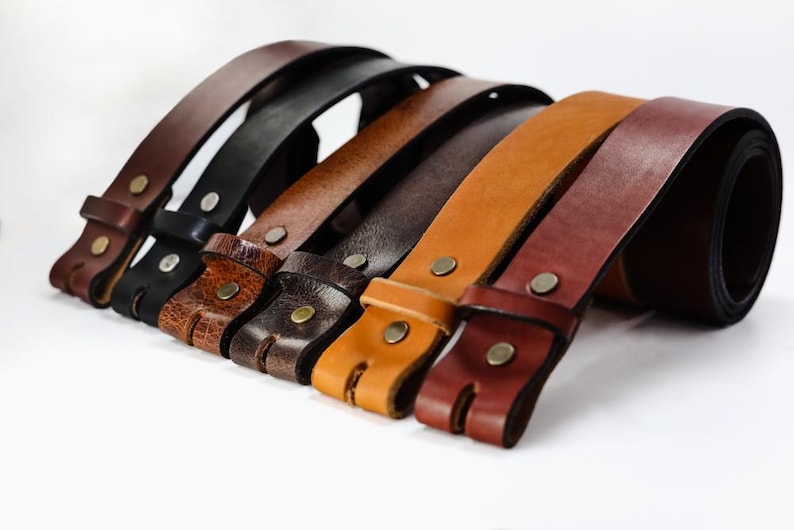 May include: A set of six leather belts in various shades of brown, including black, dark brown, light brown, and tan. The belts are all made of high-quality leather and have a simple, classic design.