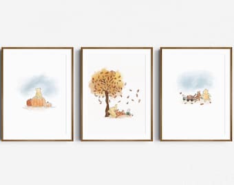May include: Set of three framed watercolor prints featuring Winnie the Pooh and friends. One print shows Pooh sitting on pumpkins, another depicts a tree with falling leaves, and the third shows the characters with a wagon.