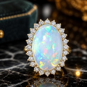 May include: An oval-shaped opal ring featuring a central cabochon opal with iridescent flashes of blue, green, and orange. The opal is surrounded by a halo of small, round, brilliant-cut white diamonds set in a yellow gold band and setting.