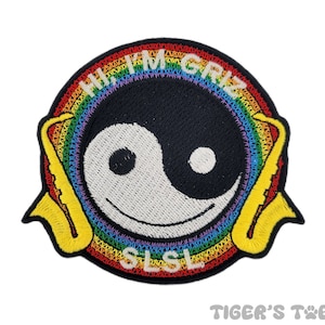May include: Embroidered patch featuring a rainbow background and a yin yang symbol with a smiling face. The text "I'm GRIZ" is written in a rainbow arc above the symbol. Two yellow saxophones are on either side of the symbol.