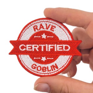 May include: Embroidered patch with a red banner and white text that reads "CERTIFIED RAVE GOBLIN." The patch is circular with a white border and a red banner across the centre. Two small stars are on the top and bottom.