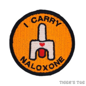 Puede incluir: Parche redondo bordado de color naranja y negro con el texto "I Carry Naloxone" y una silueta blanca de una persona sosteniendo una jeringa con un corazón rojo.