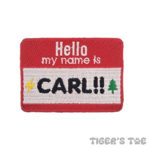 May include: Red embroidered name tag with white text that reads "Hello my name is CARL!" with a lightning bolt and a green pine tree on either side of the name.