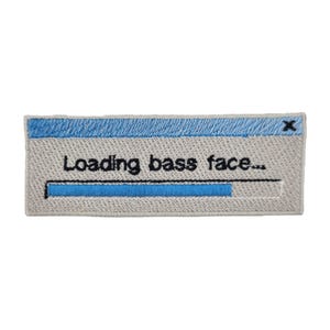 May include: Embroidered patch with a light grey background, a blue top border, and the text "Loading bass face..." in black. A blue progress bar is partially filled. The patch is rectangular.