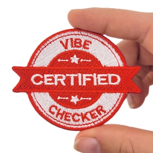 May include: Embroidered patch with a circular design. The patch features a red banner with the word "CERTIFIED" in white, and the words "VIBE CHECKER" in white. The patch is held by a hand.