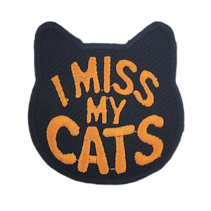 May include: A black cat-shaped patch with the embroidered text "I MISS MY CATS" in orange. This patch is a charming accessory for cat lovers, suitable for jackets, bags, or other fabric items.