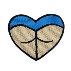 May include: Embroidered heart-shaped patch with a blue top and a tan bottom, resembling a stylized butt. The patch has a black border and black lines to define the design. The patch is on a white background.