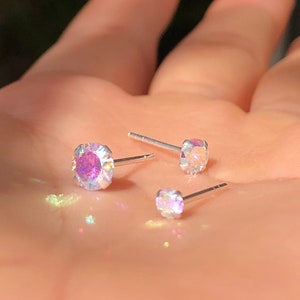 Puede incluir: Tres pendientes de botón de plata con piedras transparentes iridiscentes de diferentes tamaños.