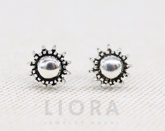 May include: A pair of silver sun stud earrings with a textured design. The earrings are small and delicate.