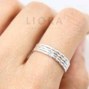May include: Set of four silver stacking rings with a textured finish. Each ring is 1 mm wide.