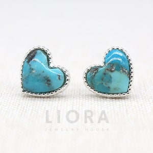 Op de afbeelding: Een paar zilveren hartvormige oorbellen met turquoise stenen. De oorbellen hebben een parelrand.