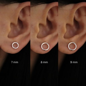 May include: Three silver hoop earrings in different sizes, 7 mm, 8 mm, and 9 mm, shown on a person's earlobe.