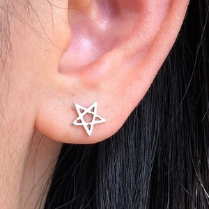 May include: A close-up of a person's ear with a small silver star-shaped earring.