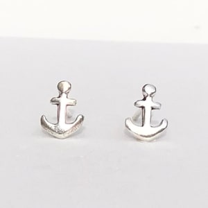 Puede incluir: Un par de pendientes de plata con forma de ancla. Las ancras son pequeñas y sencillas, con un diseño clásico.