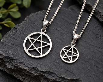 Puede incluir: Dos collares de tono plateado con colgantes de pentagrama circulares de diferentes tamaños. Cada colgante cuelga de una delicada cadena de tono plateado. El metal tiene un acabado pulido y el diseño consiste en una estrella de cinco puntas encerrada en un marco circular, creando una apariencia geométrica clara y simétrica.