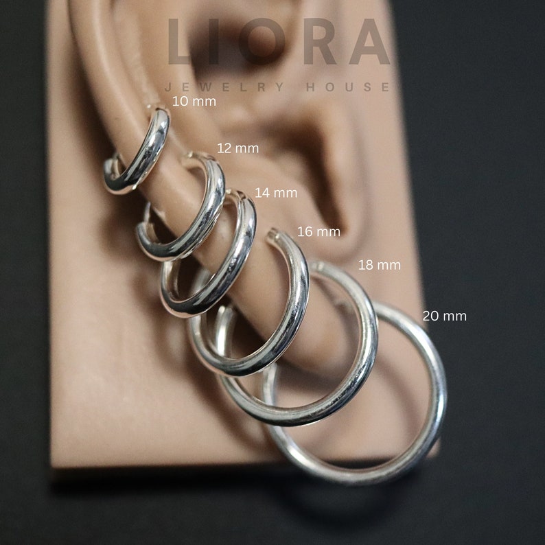 Puede incluir: Un conjunto de seis aros de plata de diferentes tama&ntilde;os, que van desde los 10 mm hasta los 20 mm de di&aacute;metro. Los pendientes se muestran en la oreja de un maniqu&iacute;.