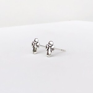May include: A pair of silver angel stud earrings. The angel is depicted in a simple, minimalist style.