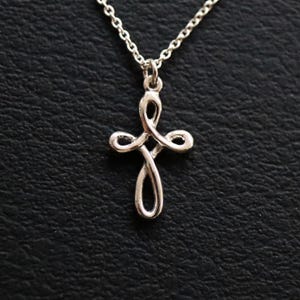 May include: A silver chain necklace with a delicate, twisted cross pendant.