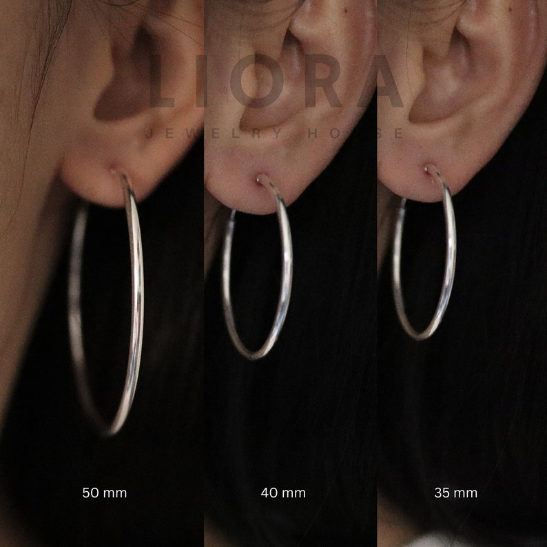 Puede incluir: Tres pendientes de aro de plata en diferentes tama&ntilde;os: 50 mm, 40 mm y 35 mm. Los pendientes se muestran en la oreja de una persona.