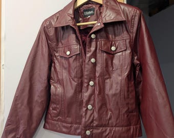May include: A burgundy faux leather jacket with a button closure and two front pockets. The jacket has a label that reads "Ellabee".