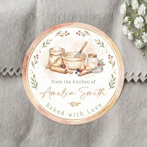 May include: A circular sticker featuring a watercolor illustration of baking supplies including a flour sack, mixing bowl, rolling pin, and whisk. The text reads from the kitchen of Amelia Smith and Baked with Love in a soft peach and green border.