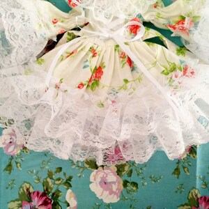 May include: A white lace dress with a floral print and a white satin ribbon tied at the waist.