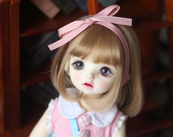 Peut inclure: Une poupée aux cheveux blonds et un bandeau rose avec un nœud. La poupée porte une robe rose et blanche avec un ruban bleu.