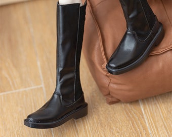 May include: A pair of black knee-high boots with a pointed toe and a low heel.