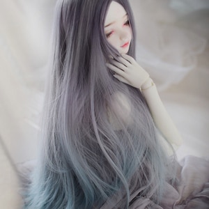 May include: A long, straight, ombre doll wig with a dark gray to light blue gradient. The wig is styled with a center part and falls to the doll's waist.