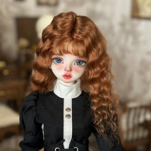 May include: A doll with long, curly, auburn hair and blue eyes. She is wearing a black and white dress with a white collar.