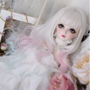 May include: A porcelain doll with long, white hair, streaked with pink and blue. The doll has large, expressive eyes, rosy cheeks, and a delicate lace collar. A pearl necklace adorns the doll's neck. The doll is surrounded by flowers.